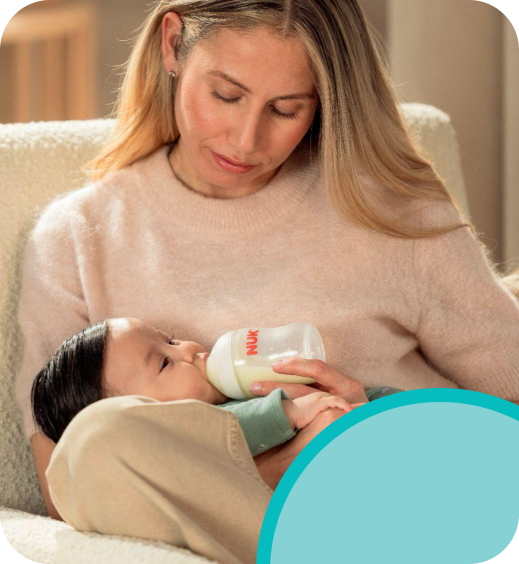 Parent bottle-feeding their baby with a NUK bottle