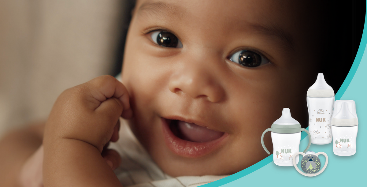 Smiling baby with NUK bottles, cups and soothers